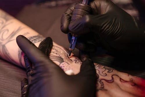 A close-up of a tattoo artist using a tattoo machine on a person's arm