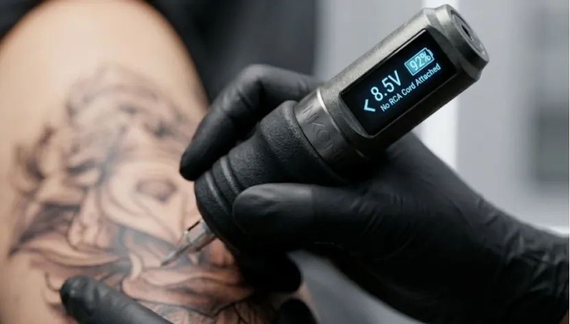 Close-up of ergonomic wireless tattoo machine with LED voltage display.