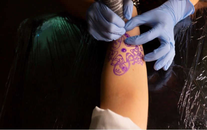 A tattoo artist at a tattoo studio is designing a tribal arm tattoo
